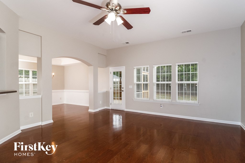 A spacious room with a ceiling fan and wooden flooring.