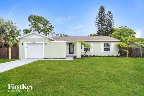 a small white house with a lawn and a garage