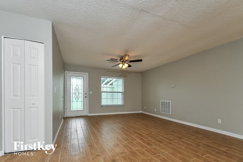 the living room and dining room with wood floors and a ceiling fan