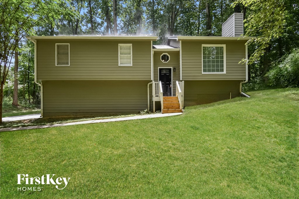 A house with a garage door is shown in a forest.