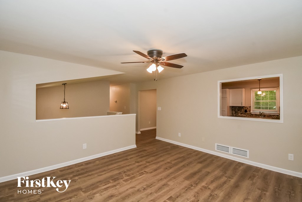 A spacious room with a ceiling fan and wooden flooring.
