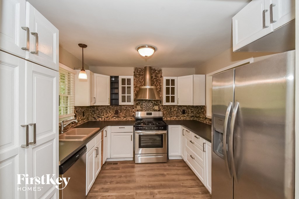A kitchen with a stainless steel refrigerator and a black countertop.