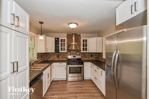 A kitchen with a stainless steel refrigerator and a black countertop.