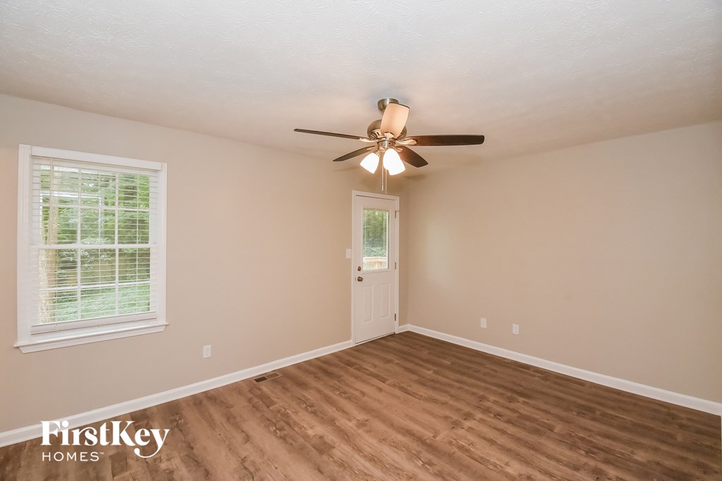 A room with a ceiling fan and wooden flooring.
