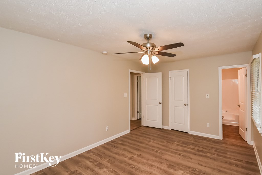 A spacious room with a ceiling fan and wooden flooring.