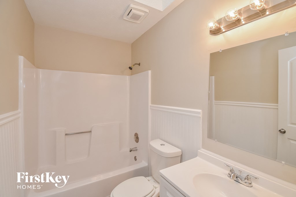 A white bathroom with a toilet, sink, and tub.