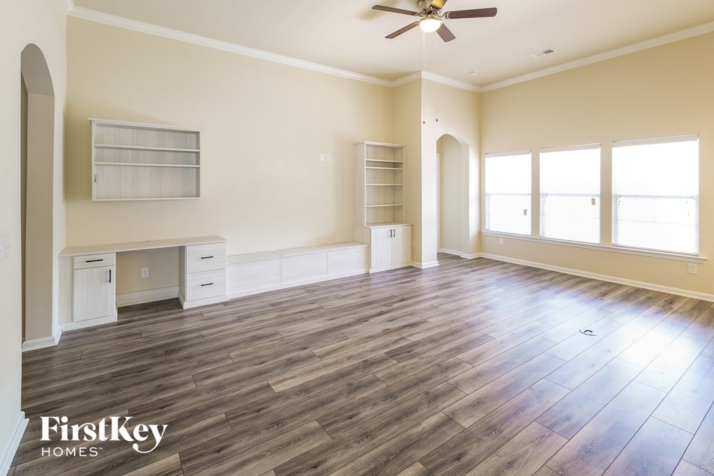 an empty living room with wood floors and a ceiling fan