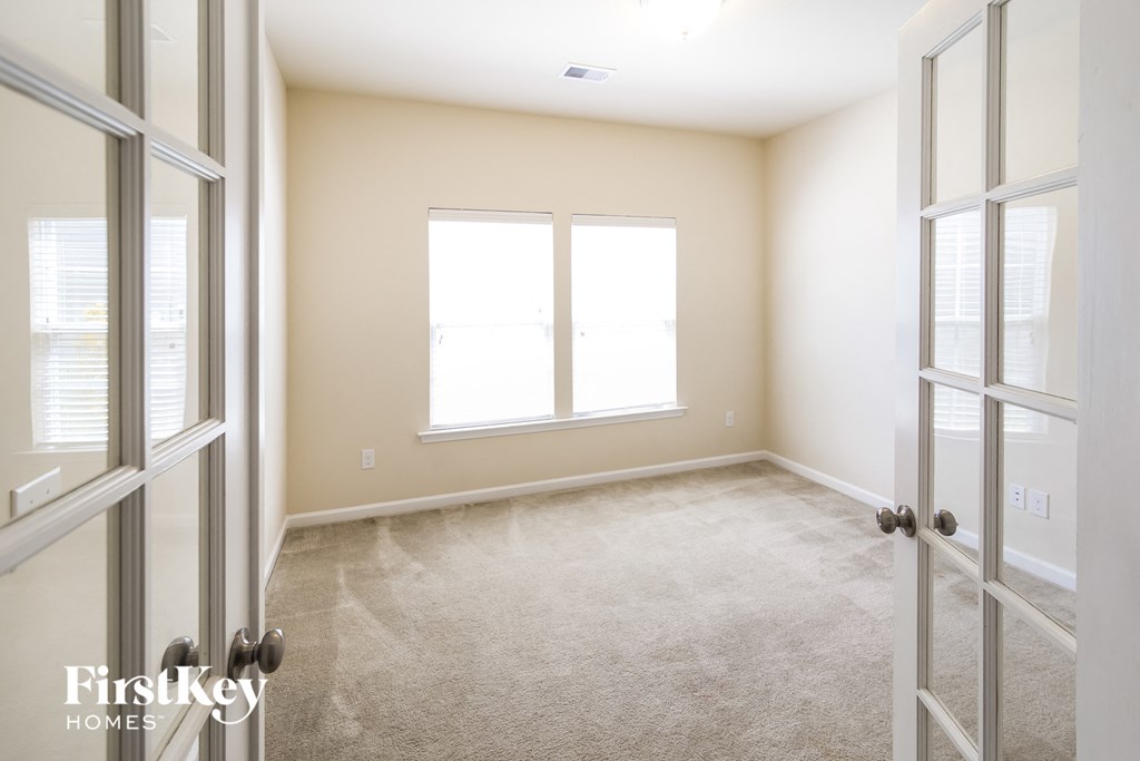 a bedroom with two windows and a carpeted floor