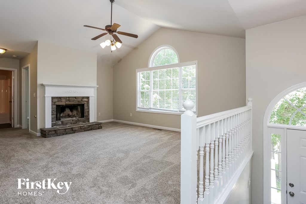 A spacious room with a fireplace and a ceiling fan.