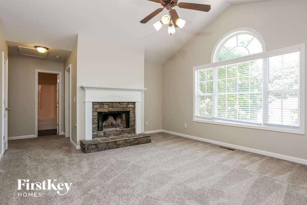 A spacious living room with a fireplace and a ceiling fan.