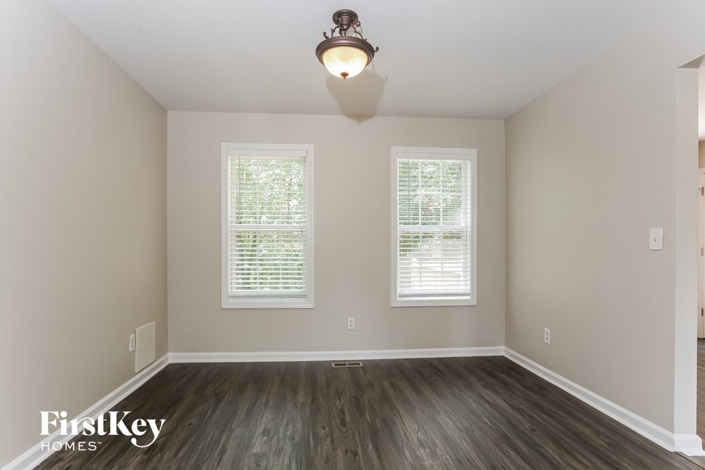 A room with a wooden floor and two windows.