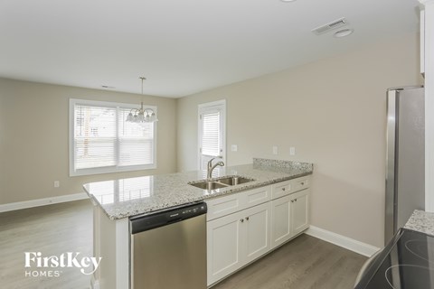 a kitchen with white cabinets and granite counter tops and a stainless steel refrigerator