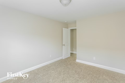 a bedroom with white walls and carpet and a door to a closet