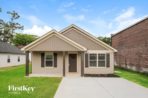 a small brown house with a sidewalk in front of it