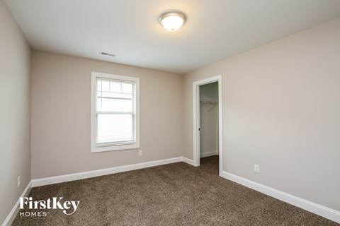a bedroom with carpet and a window and a door to a closet