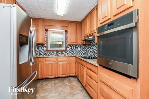 A kitchen with wooden cabinets and a stainless steel refrigerator.