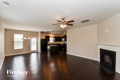 A spacious living room with a fireplace and a ceiling fan.