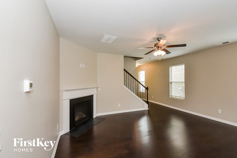 A spacious room with a fireplace and a staircase.