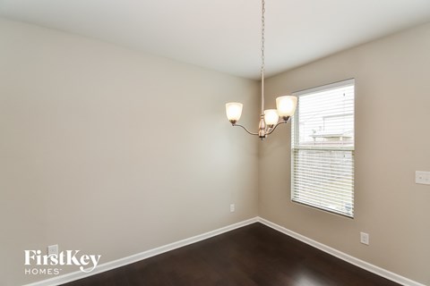 A room with a chandelier and a window with blinds.