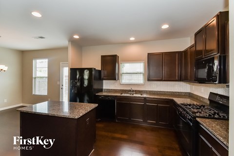 A kitchen with dark wood cabinets and a granite countertop.