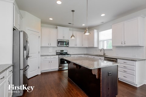 a kitchen with white cabinets and a marble counter top