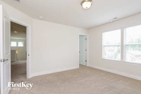 the living room and dining room of a home with white walls and carpet