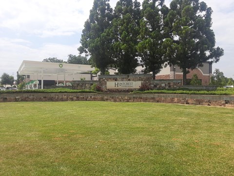 A grassy field in front of a building with a sign that says "Huntcliffe".