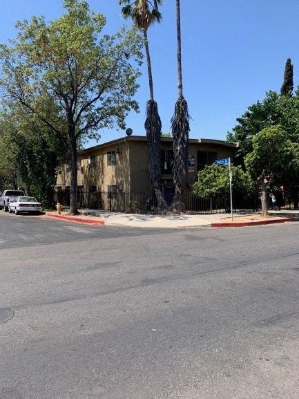 a building on the corner of a street with palm trees