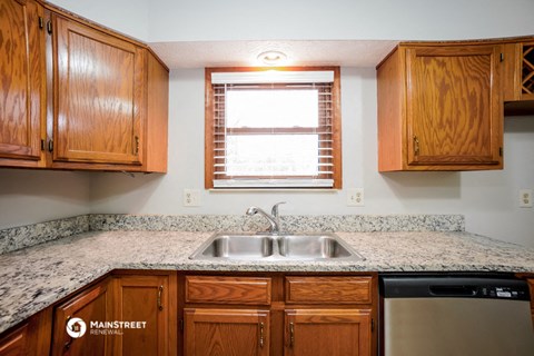 a kitchen with wooden cabinets and granite counter tops and a sink