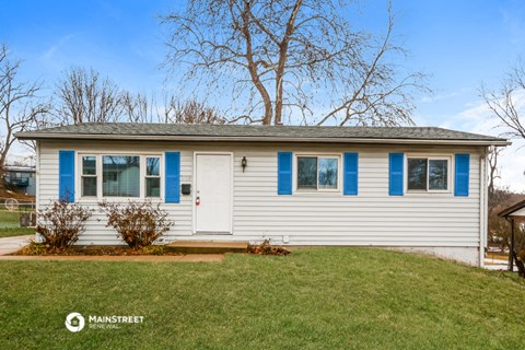 a small white house with blue shutters and a lawn