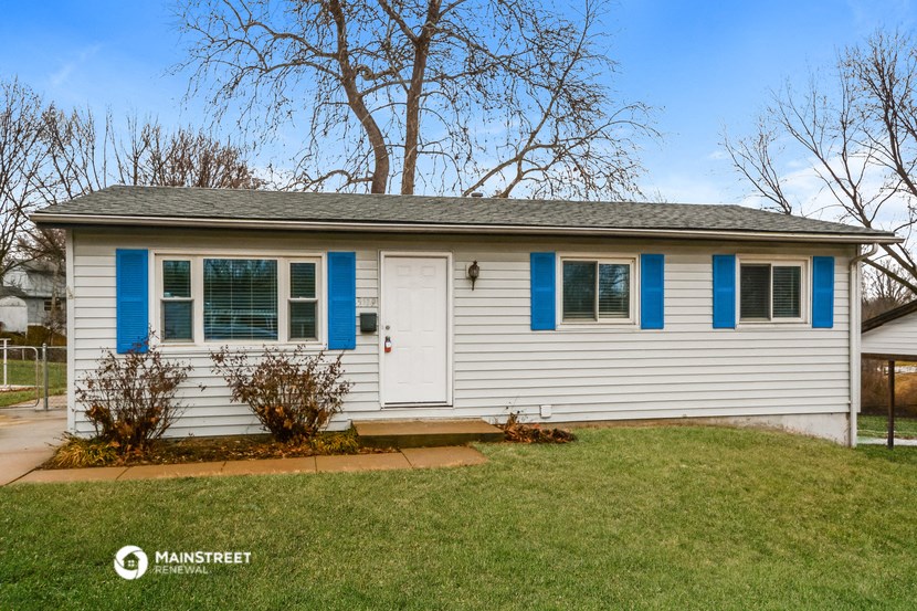a white house with blue shutters and a lawn