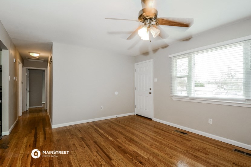 the living room and dining room with wood flooring and a ceiling fan