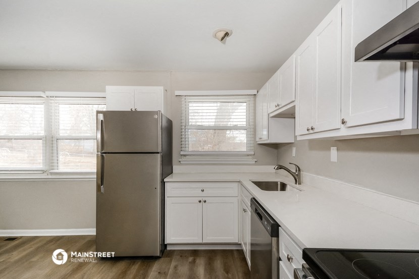 a white kitchen with white cabinets and a stainless steel refrigerator