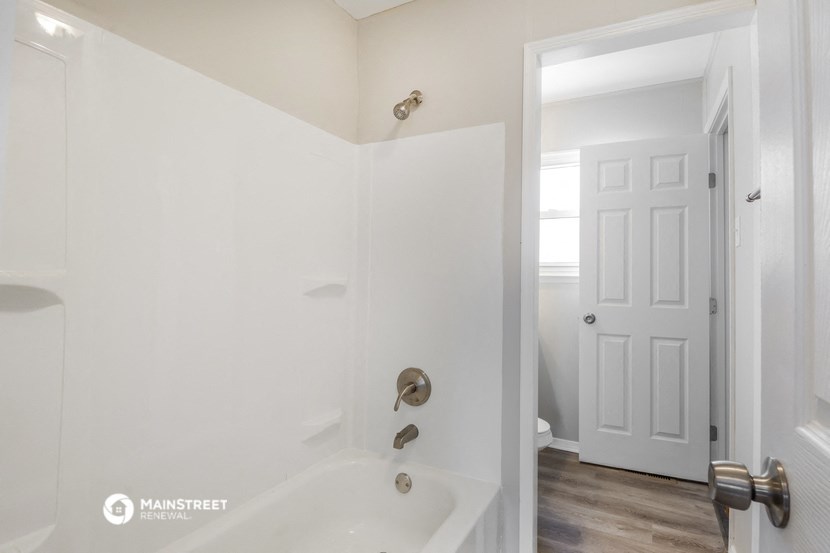 a white bathroom with a tub and a white door
