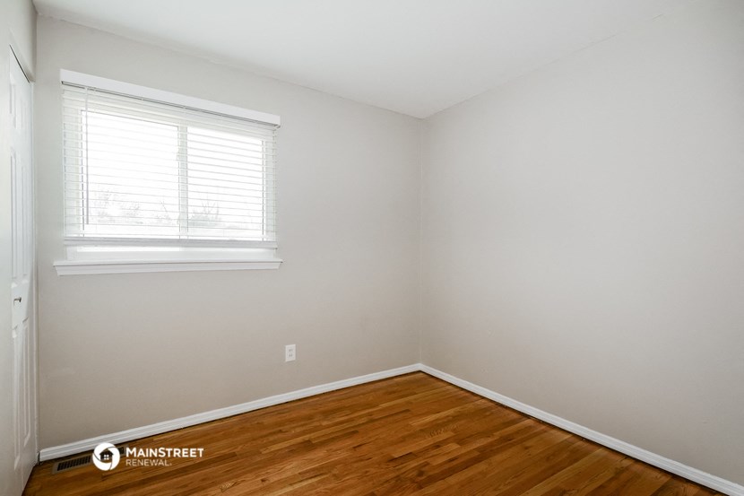 a bedroom with wood floors and a window