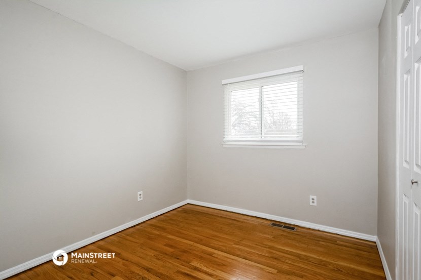 the living room of a home with wooden floors and a window