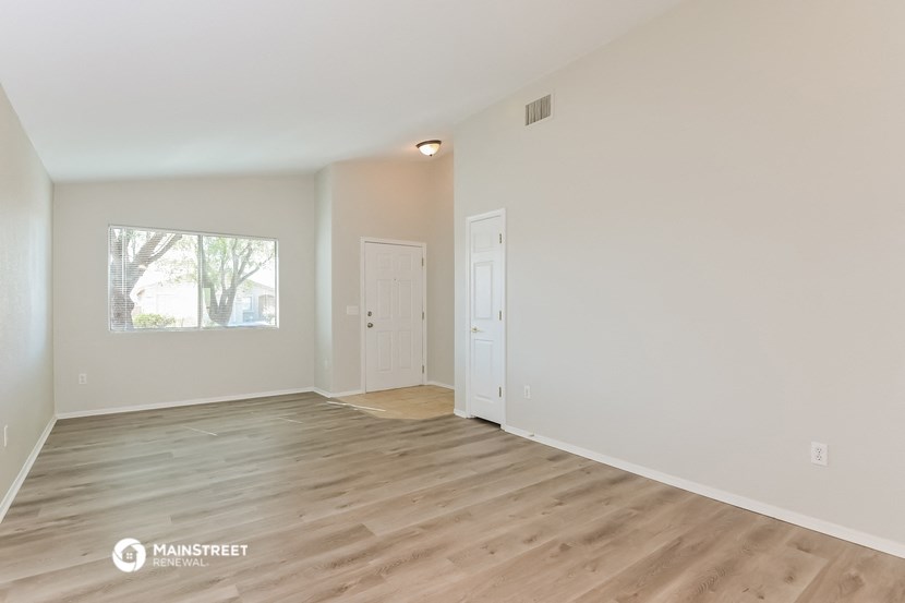 the spacious living room with wood flooring and white walls