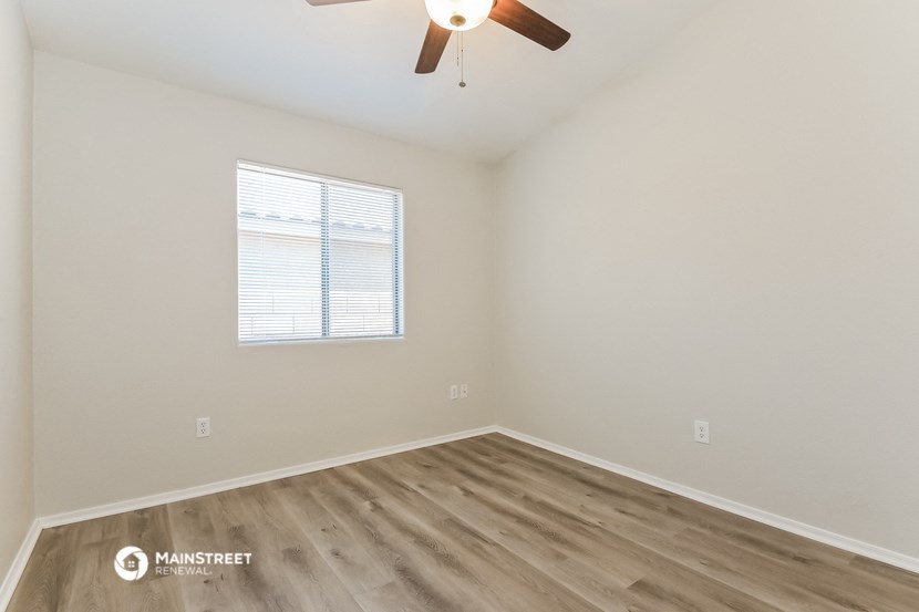 the spacious living room with wood flooring and a ceiling fan