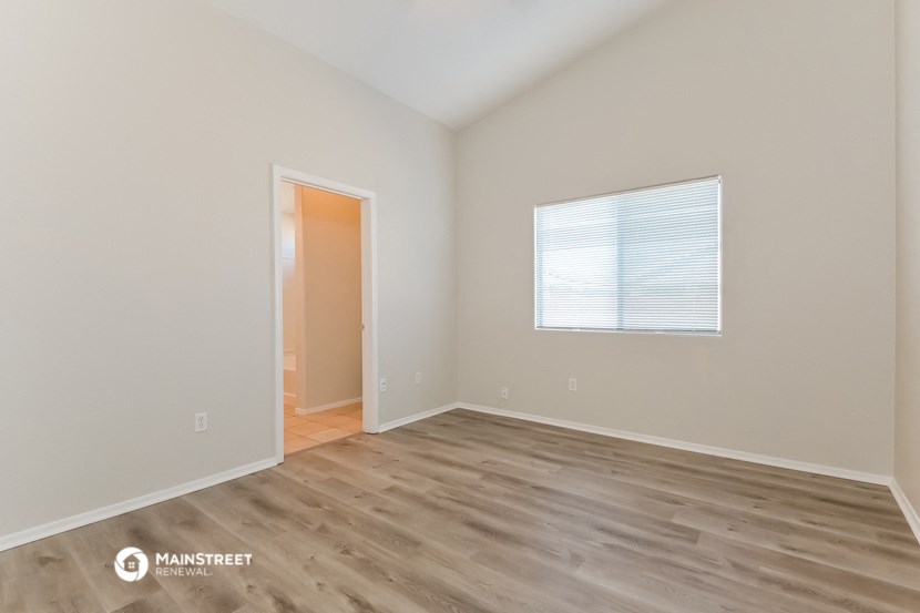 the living room of an apartment with wooden floors and a window