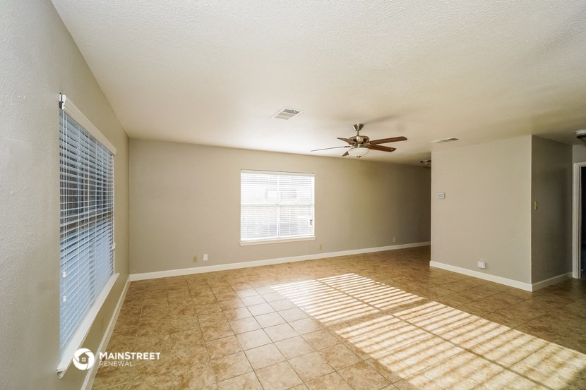 an empty living room with a ceiling fan