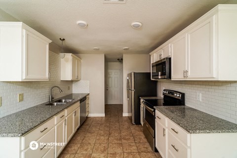 a kitchen with white cabinets and granite counter tops