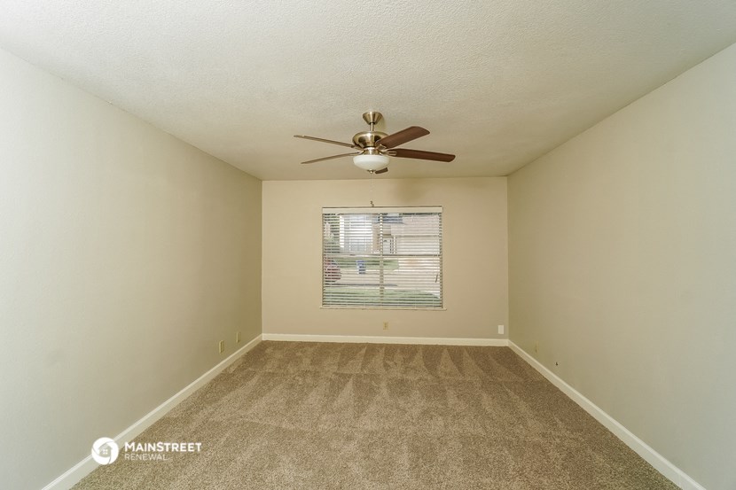 an empty room with a ceiling fan and a window