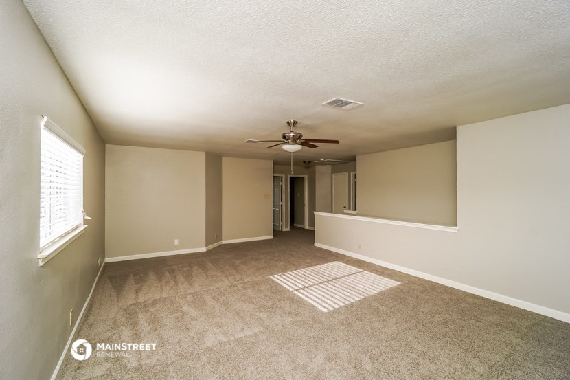 an empty living room with a ceiling fan