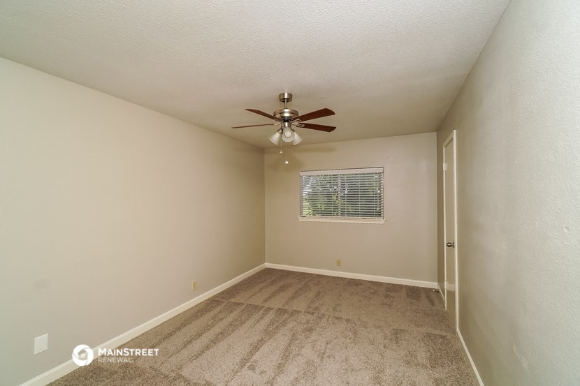 the living room of an empty bedroom with a ceiling fan