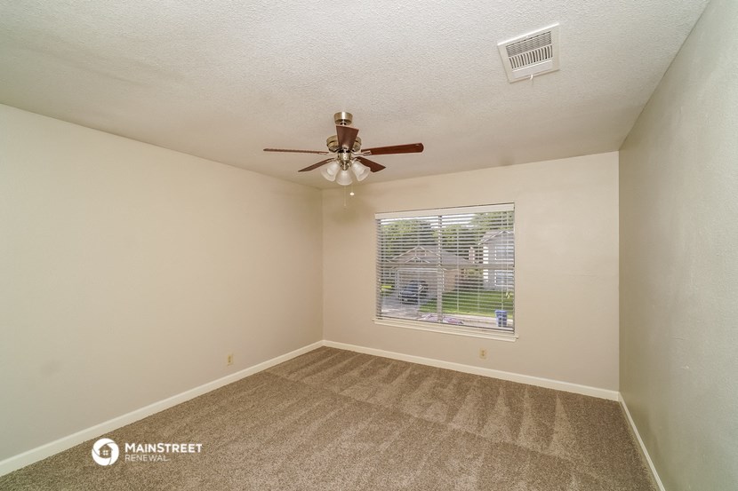an empty bedroom with a ceiling fan and a window