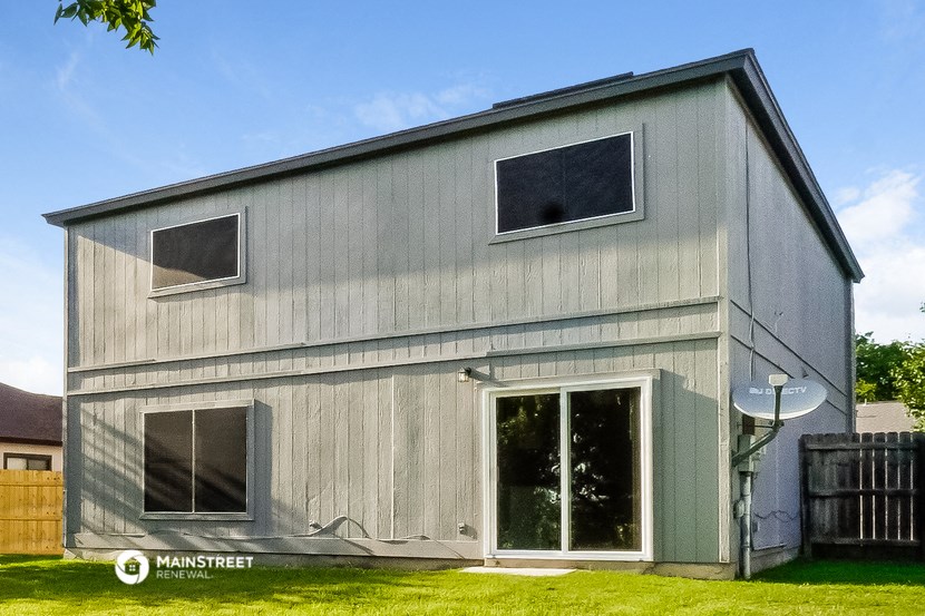 a gray barn with a door and windows