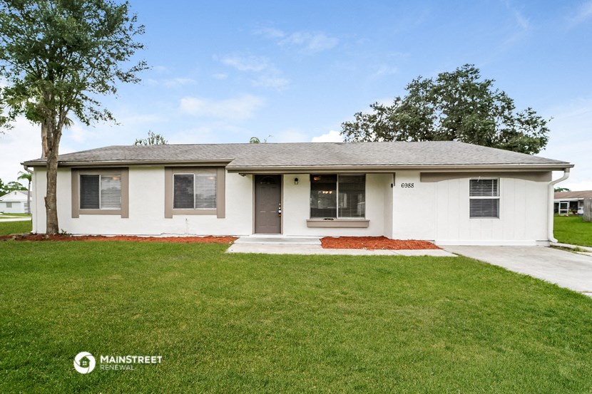 a white house with a lawn and a tree