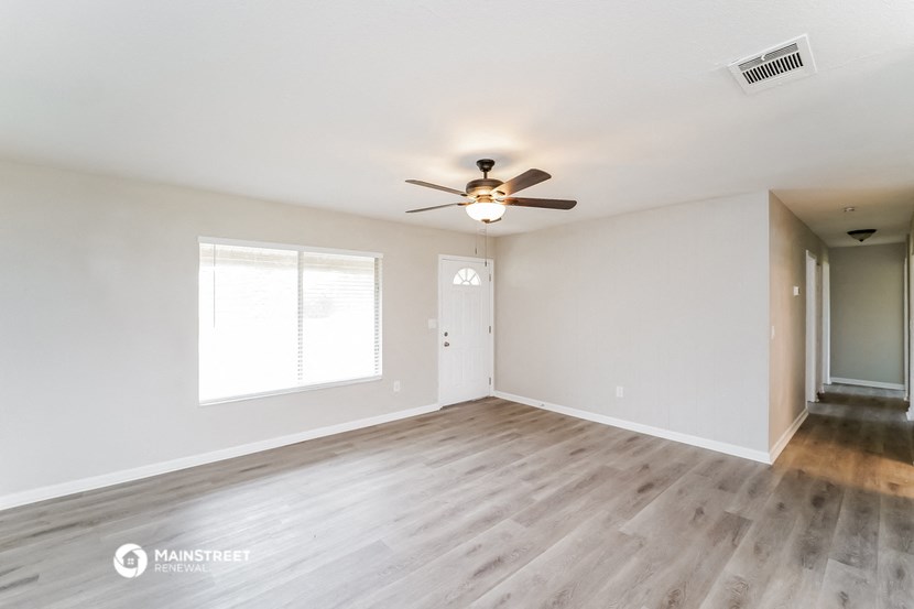 the spacious living room with hardwood floors and a ceiling fan