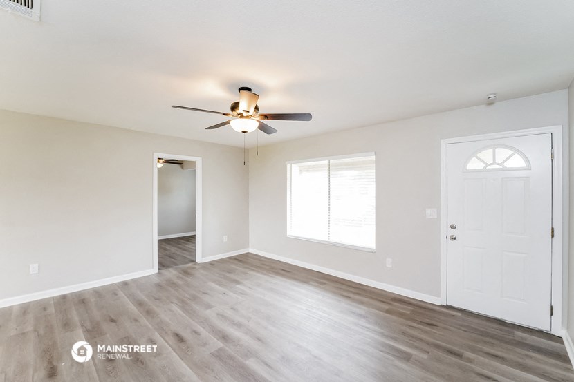 an empty living room with white walls and a ceiling fan