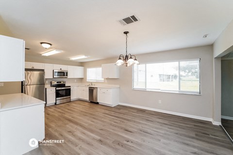 the kitchen and living room of an apartment with white cabinets and stainless steel appliances